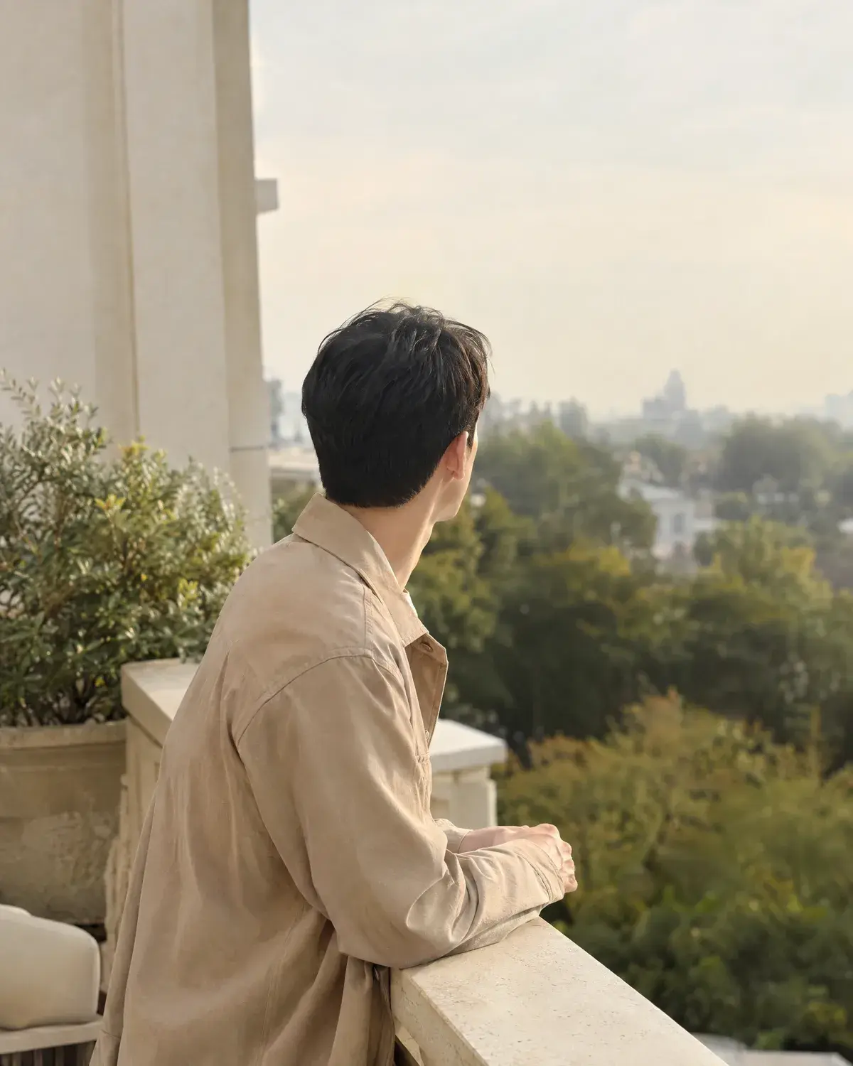 테라스 난간에 기대 먼 곳을 보는 남성의 옆뒤가 정돈된 짧은 머리 뒷모습